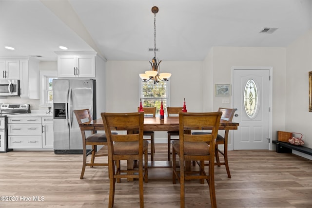 dining space featuring an inviting chandelier and light wood-type flooring