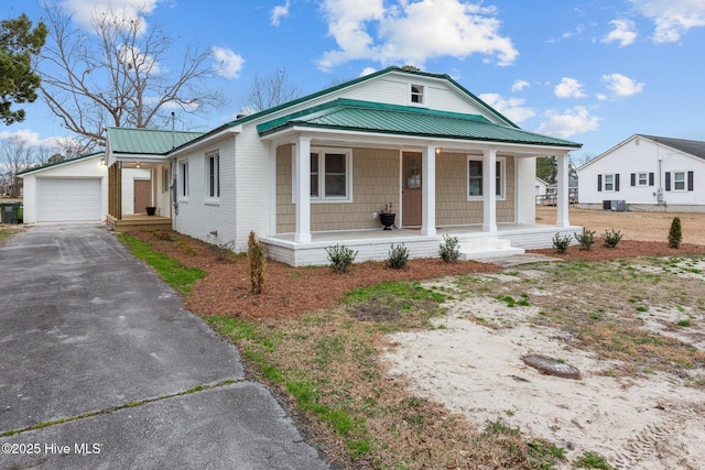 view of front of home with a garage, metal roof, aphalt driveway, an outbuilding, and a porch