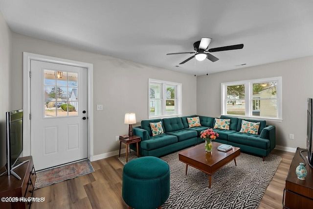 living area with a ceiling fan, visible vents, baseboards, and wood finished floors