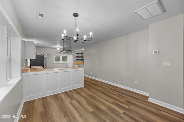 kitchen with visible vents, island exhaust hood, a peninsula, and wood finished floors