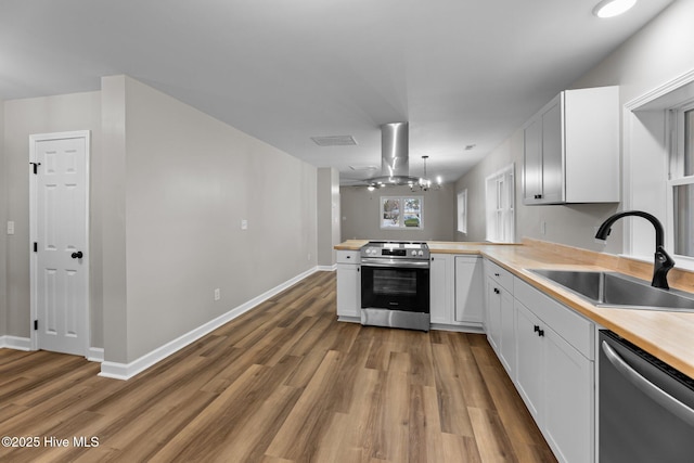 kitchen with stainless steel appliances, white cabinets, a sink, and island exhaust hood