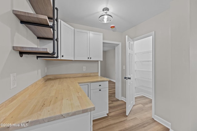 kitchen with baseboards, white cabinets, wood counters, light wood-style floors, and open shelves