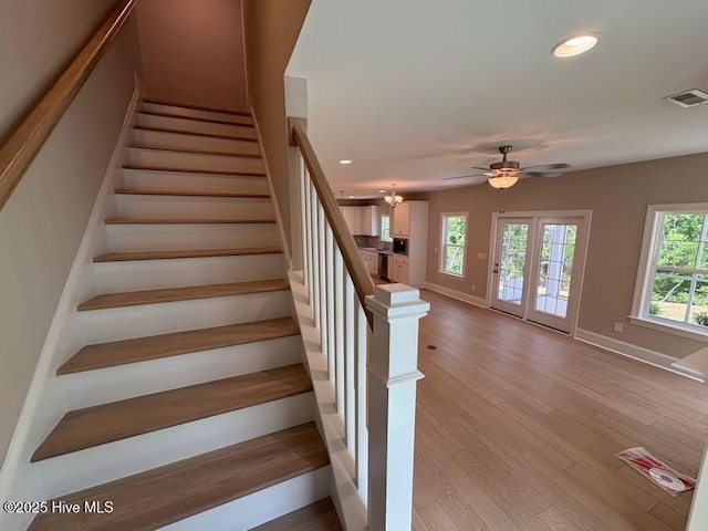 staircase with wood finished floors, baseboards, a healthy amount of sunlight, and recessed lighting