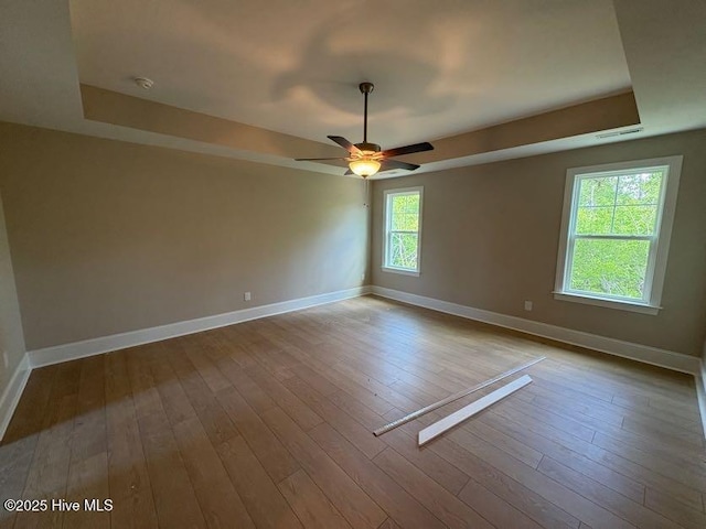 unfurnished room with a ceiling fan, visible vents, baseboards, and a raised ceiling