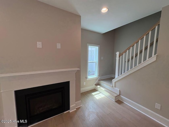 unfurnished living room with recessed lighting, baseboards, stairs, wood finished floors, and a fireplace