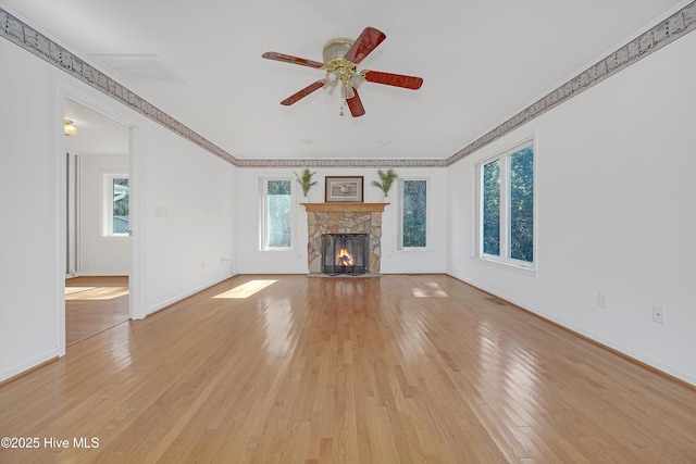 unfurnished living room featuring a fireplace, ornamental molding, ceiling fan, and light wood-type flooring