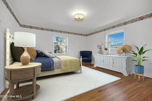 bedroom with ornamental molding and hardwood / wood-style floors