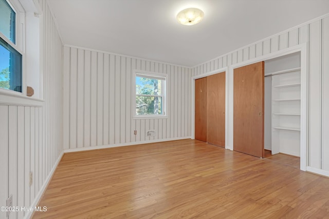 unfurnished bedroom featuring light hardwood / wood-style flooring and multiple closets