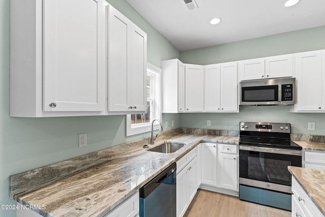 kitchen featuring white cabinetry, stainless steel appliances, light stone countertops, and sink