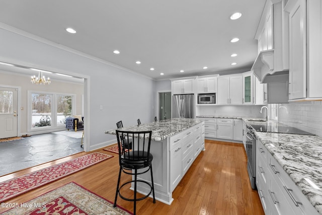 kitchen with stainless steel appliances, white cabinetry, a kitchen island, and crown molding