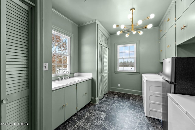 clothes washing area featuring washer / clothes dryer, crown molding, sink, and an inviting chandelier