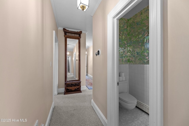 corridor with tile walls, crown molding, and light colored carpet