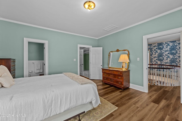 bedroom with hardwood / wood-style flooring, crown molding, a spacious closet, and ensuite bathroom