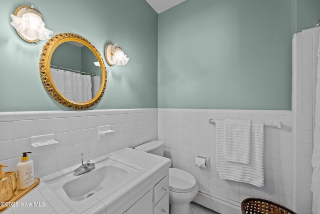 bathroom featuring vanity, toilet, curtained shower, and tile walls