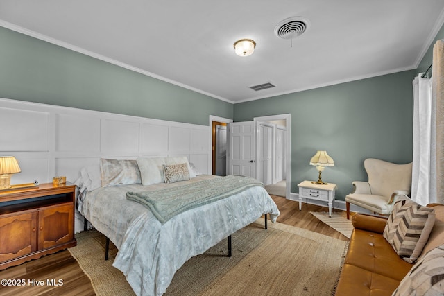 bedroom with hardwood / wood-style flooring, ornamental molding, and a closet