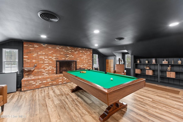 playroom with billiards, vaulted ceiling, brick wall, a fireplace, and light hardwood / wood-style floors