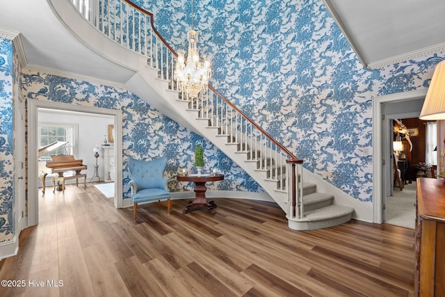 stairs featuring hardwood / wood-style floors, ornamental molding, and a high ceiling