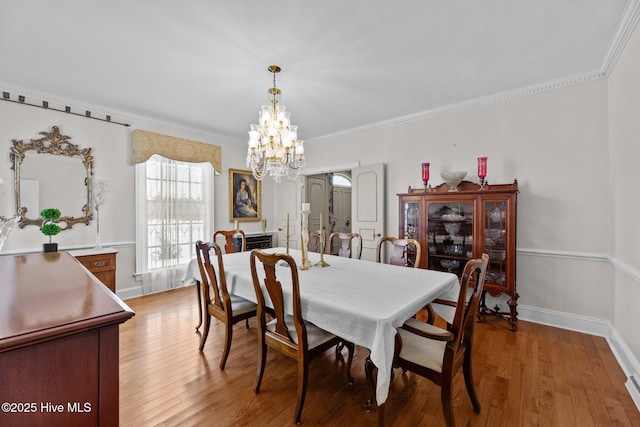 dining area with an inviting chandelier, ornamental molding, and light wood-type flooring