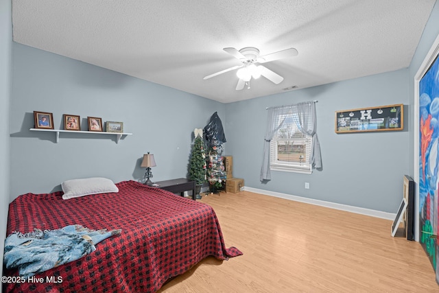 bedroom with ceiling fan, hardwood / wood-style floors, and a textured ceiling