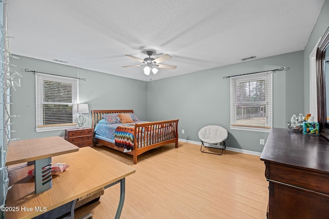 bedroom with hardwood / wood-style flooring, ceiling fan, and a textured ceiling