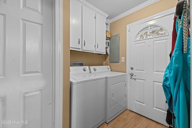 laundry room featuring washing machine and dryer, cabinets, electric panel, ornamental molding, and a textured ceiling