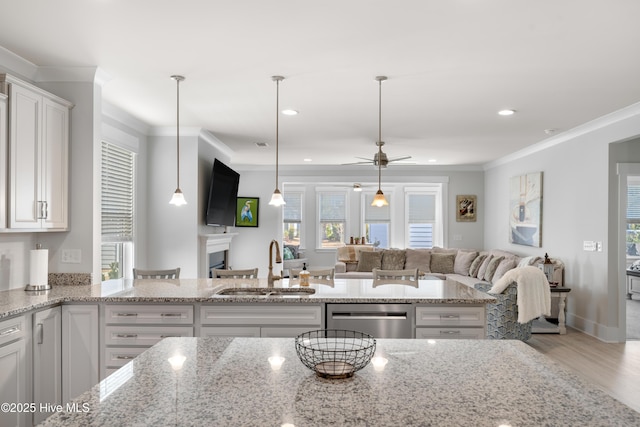 kitchen featuring decorative light fixtures, open floor plan, white cabinets, a sink, and dishwasher