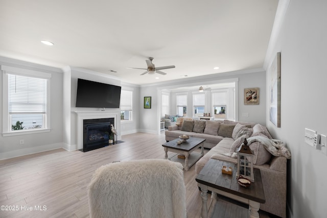 living area with ornamental molding, light wood-type flooring, a fireplace with flush hearth, and baseboards