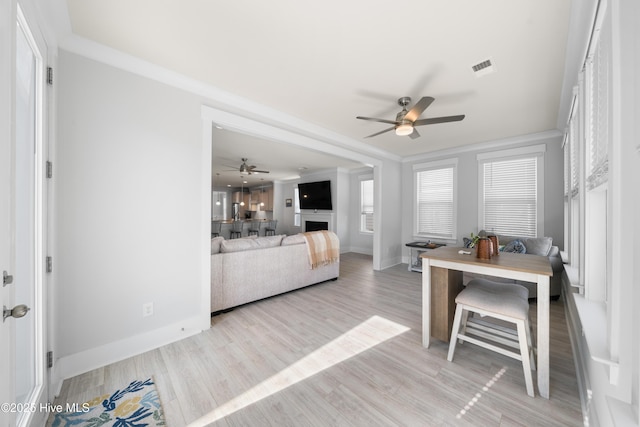 dining area featuring a fireplace, visible vents, light wood-style flooring, a ceiling fan, and baseboards