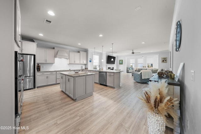 kitchen with open floor plan, decorative light fixtures, a center island, custom exhaust hood, and stainless steel appliances