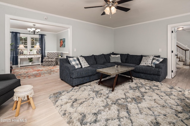 living room with wood-type flooring, ceiling fan with notable chandelier, and crown molding