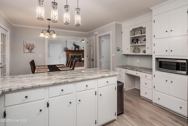 kitchen with white cabinetry, hanging light fixtures, crown molding, and a breakfast bar area