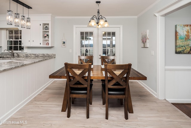 dining space featuring crown molding, sink, a chandelier, and light hardwood / wood-style flooring