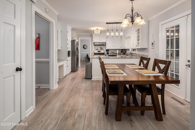 dining space with crown molding, a notable chandelier, and light wood-type flooring