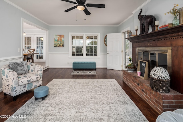 living room with a fireplace, dark wood-type flooring, ornamental molding, and ceiling fan