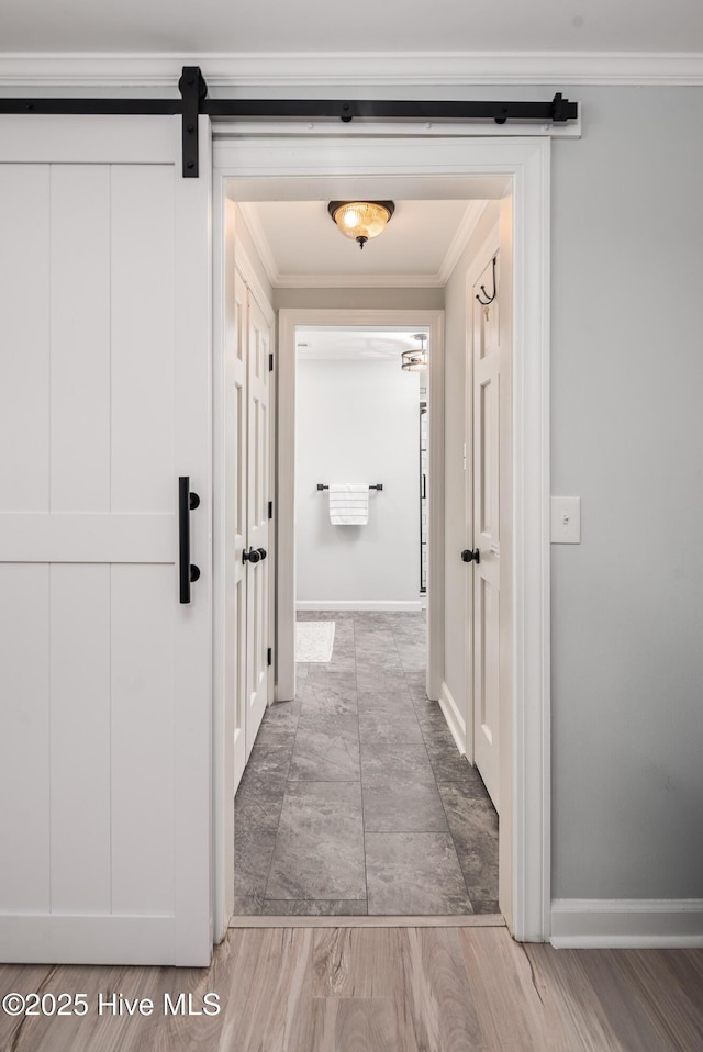 hall featuring hardwood / wood-style flooring, ornamental molding, and a barn door