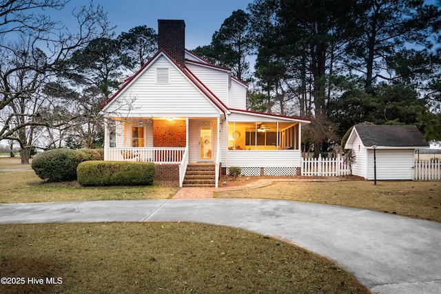 view of front of home featuring a front lawn, a storage unit, a sunroom, and a porch