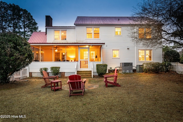 back house at dusk featuring a yard, central AC, and ceiling fan