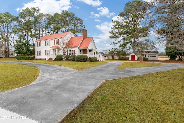 view of front of property with a storage shed, a garage, and a front yard