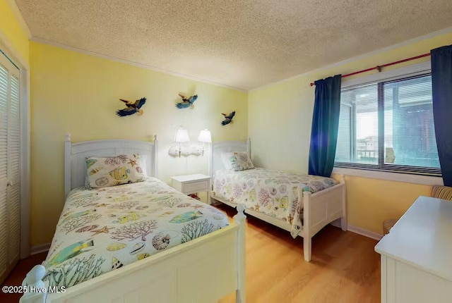 bedroom with crown molding, light hardwood / wood-style flooring, and a textured ceiling