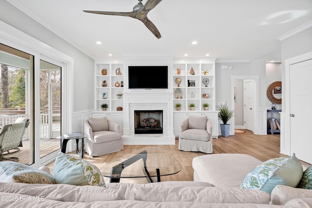 living room featuring a ceiling fan, light wood-style flooring, a fireplace, ornamental molding, and recessed lighting