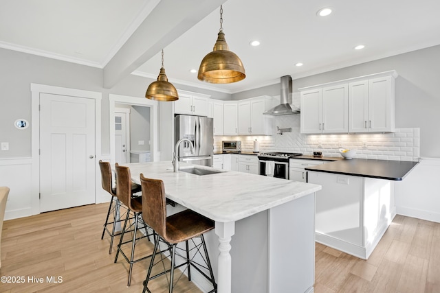 kitchen with stainless steel appliances, a sink, backsplash, wall chimney range hood, and ornamental molding
