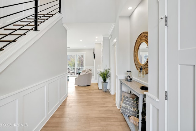 hallway with recessed lighting, a decorative wall, a wainscoted wall, and light wood-style flooring