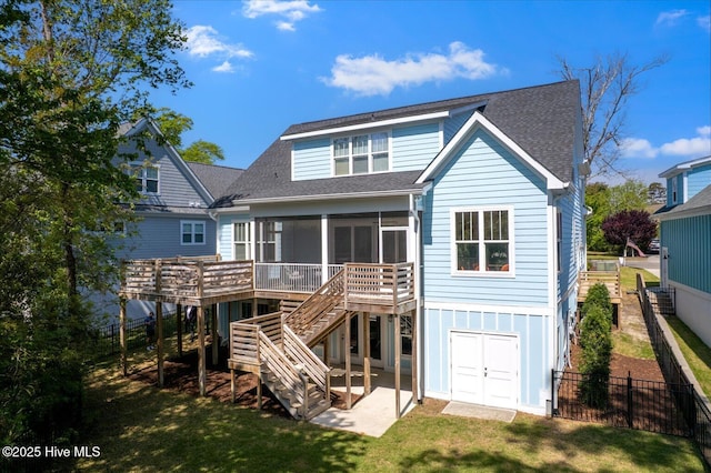 back of house featuring a shingled roof, fence, a yard, a sunroom, and stairs