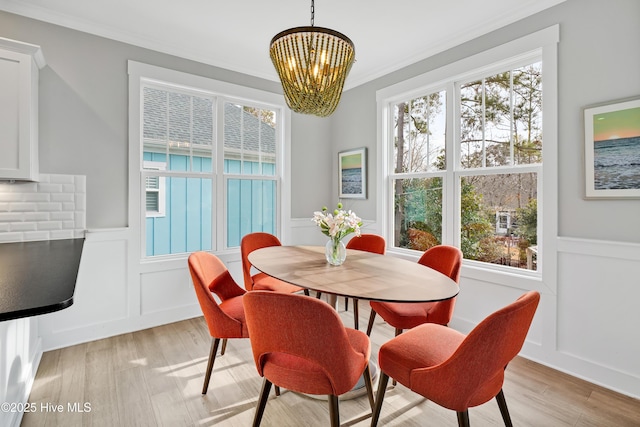 dining space featuring wainscoting, light wood-style floors, and a decorative wall