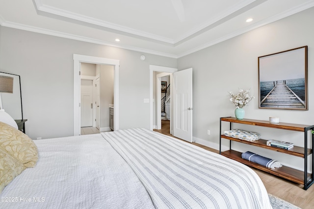 bedroom featuring a tray ceiling, wood finished floors, crown molding, and recessed lighting