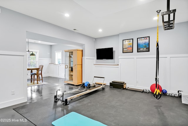 exercise area featuring a wainscoted wall, recessed lighting, and a decorative wall