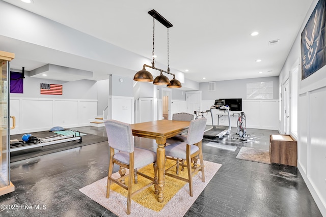 dining area with a wainscoted wall, recessed lighting, stairs, and a decorative wall