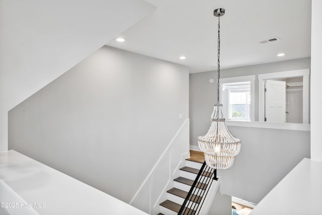 staircase featuring an inviting chandelier, recessed lighting, visible vents, and baseboards