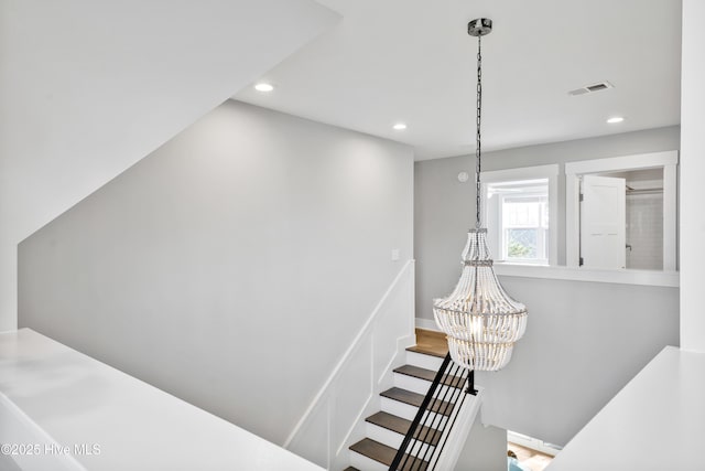 stairway with an inviting chandelier, visible vents, and recessed lighting