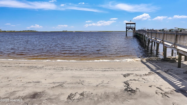 view of dock with a water view and a beach view